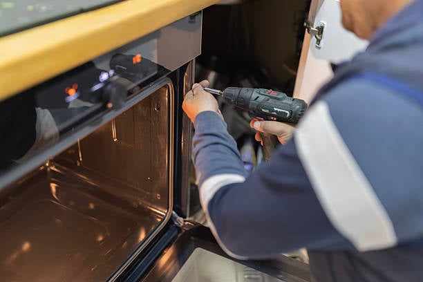 Technicus herstelt een ingebouwde oven in de keuken